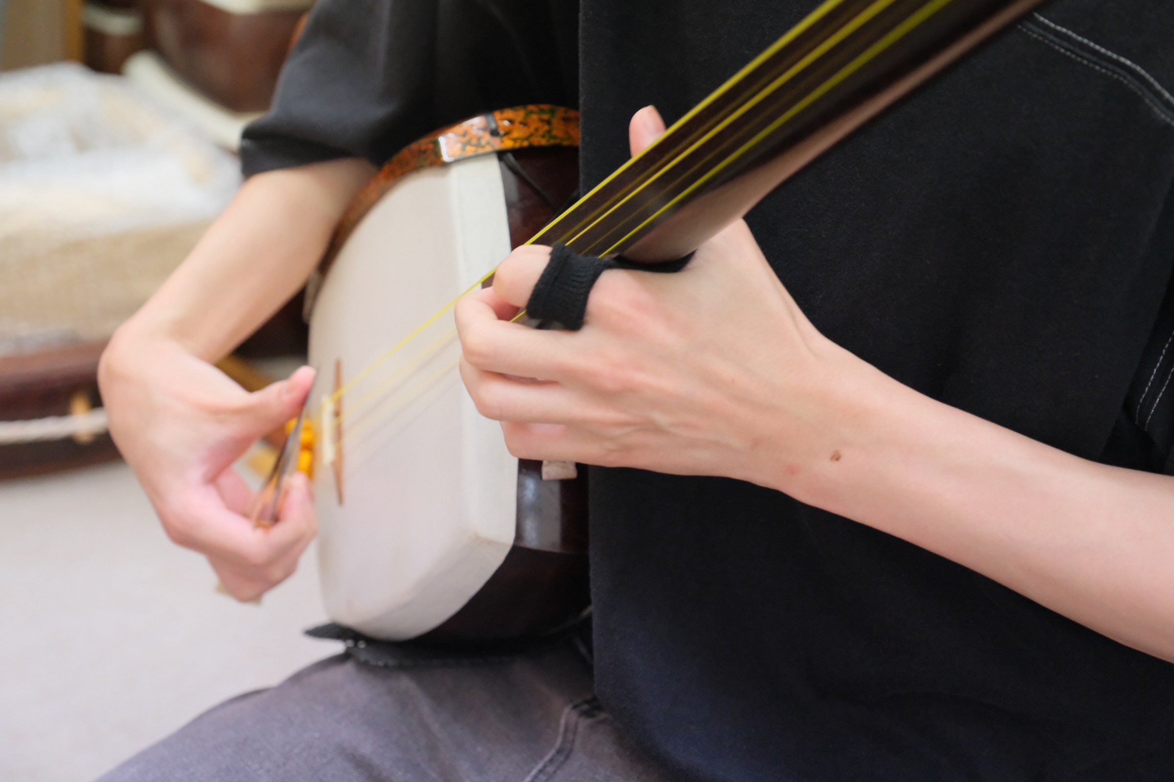 棹に指を添えて弦を押さえる手元